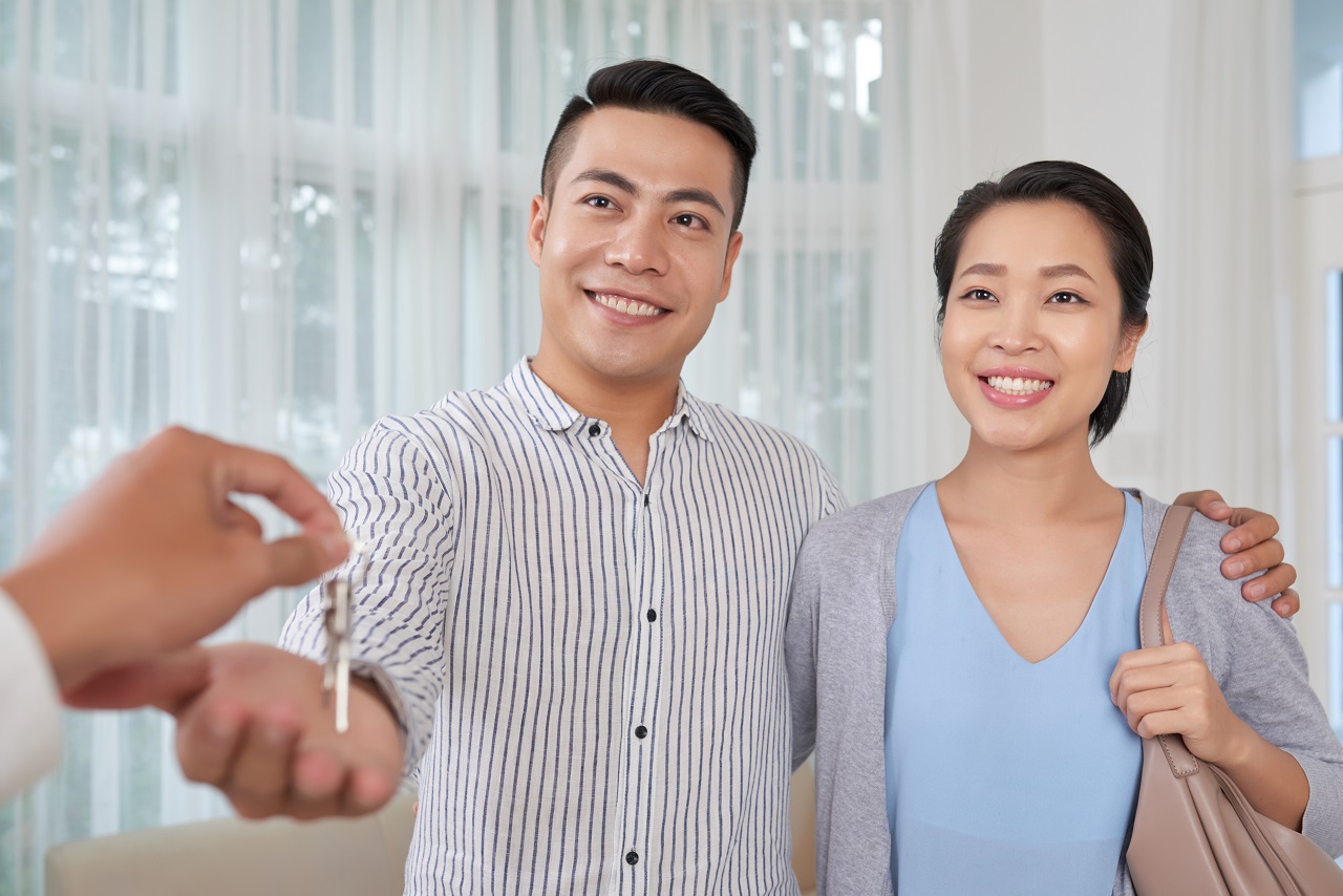 A cheerful young Asian couple receiving the keys to their new house