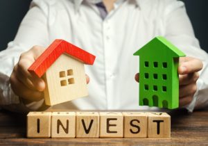 Wooden blocks shaped like houses, buildings, and the word INVEST