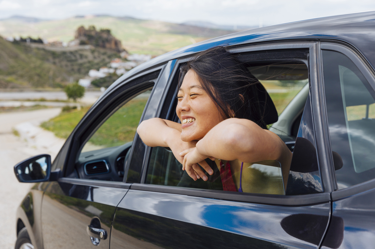A woman smiling while leaning out the car window