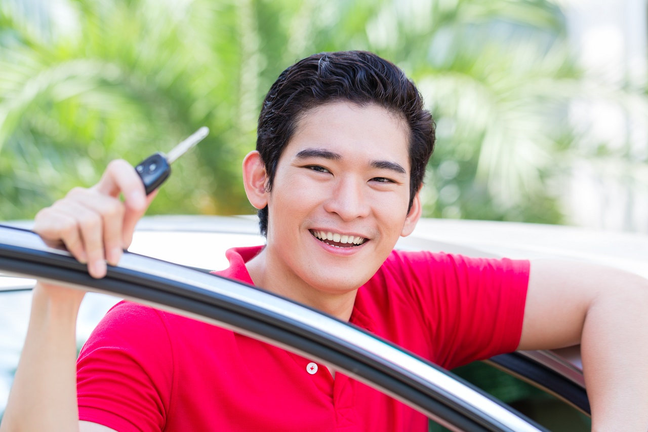 An Asian man showing his car key as loan collateral