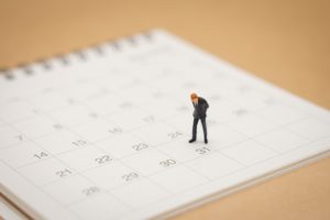 A businessman figurine looking down at a calendar