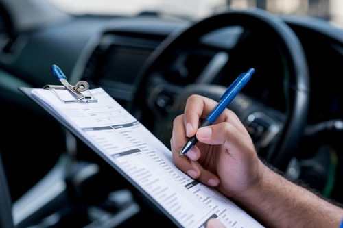 Person filling out a form with a car on the background