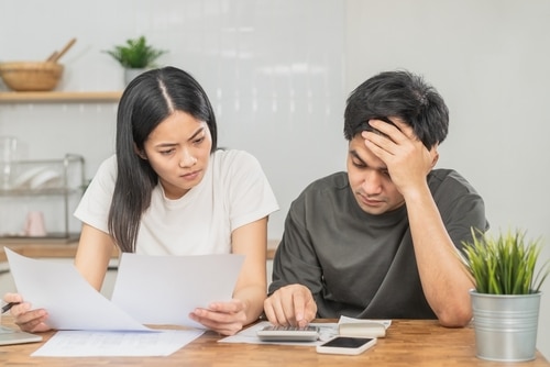 A stressed young Asian couple is looking at their finances and bills.